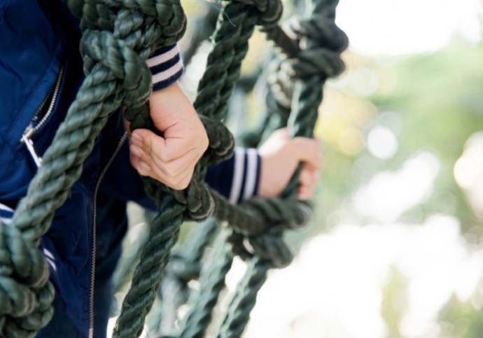 Little asian boy climbing outdoors rope frame.
