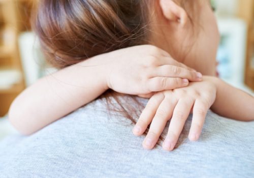 Rear view of woman embraced by her little daughter