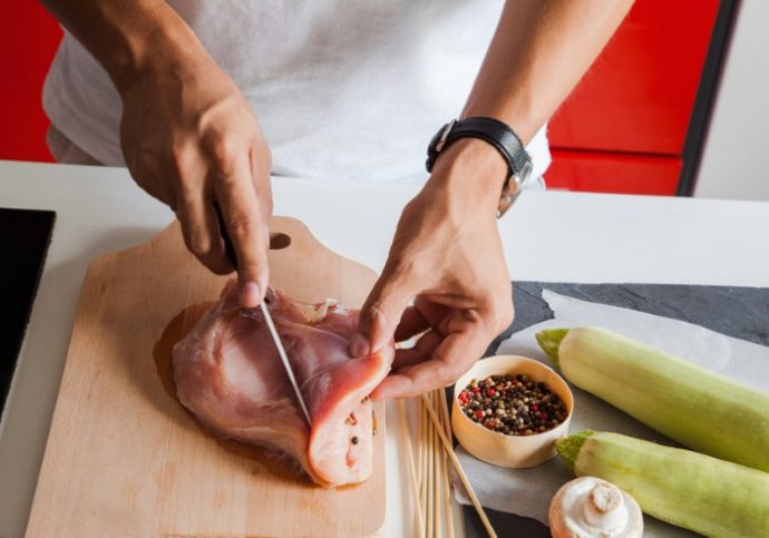 Close Up Of Man's Hands Cutting Raw Turkey Fillet For Skewers