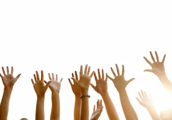Raised arms of people against white background