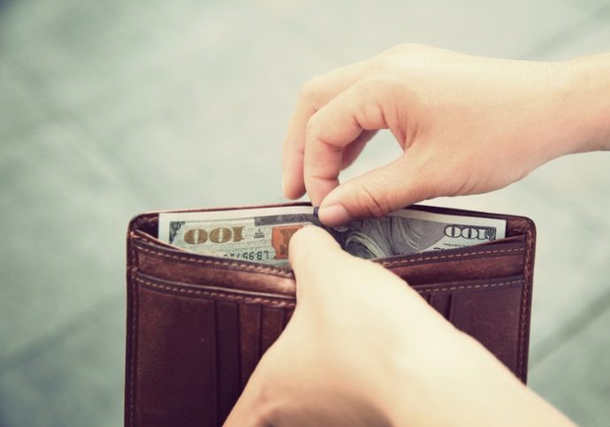 Hands taking out money from wallet on street