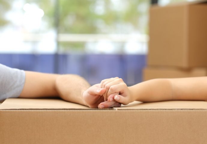 Couple holding hands over a box moving home