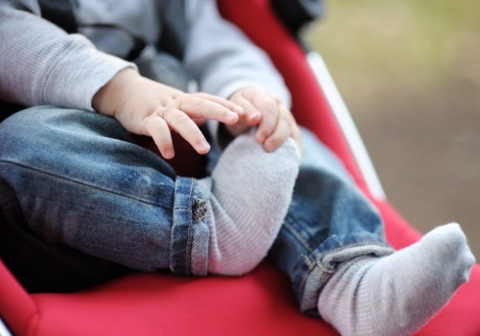 Little baby boy in stroller playing with his sock
