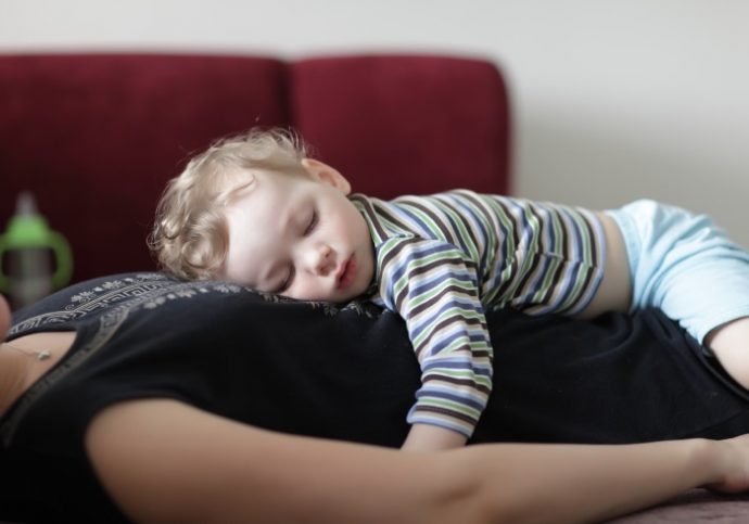 Child is sleeping on his mother at home