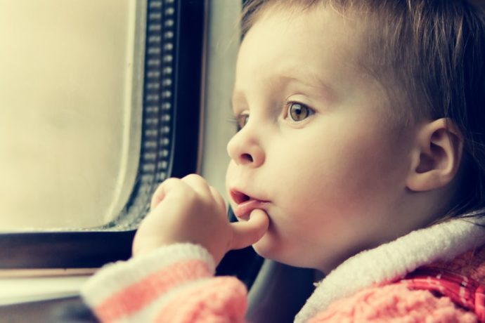 A boy rides on a train and looking out the window.