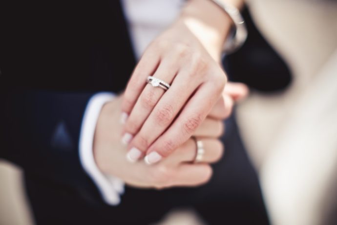 Close up of holding hands with wedding rings