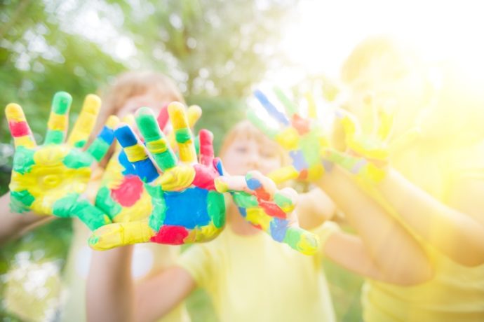 Group of friends with painted hands against green spring background