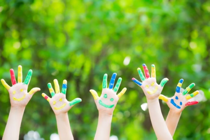 Group of smiley hands against green spring background