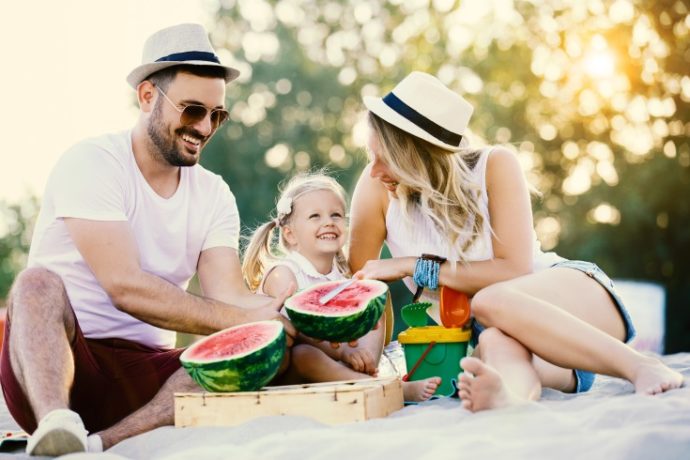 Happy family is enjoying beach and eating watermelon.