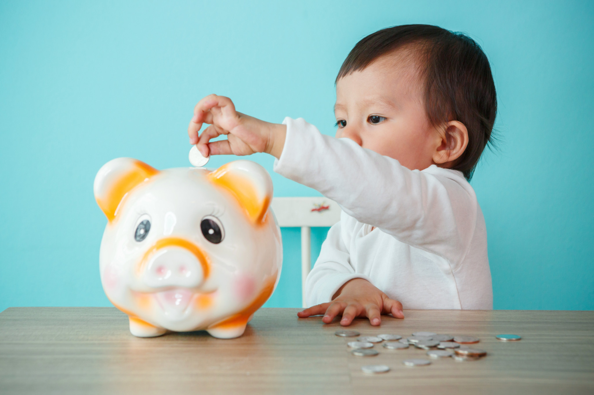 little baby moneybox putting a coin into a piggy bank – kid savi