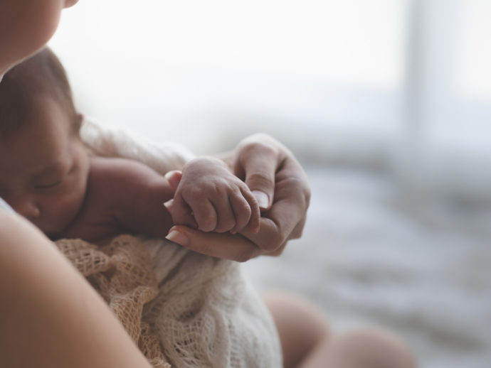Close up Mother holding hands Asian female newborn baby and sunlight in the morning. Cute little girl three weeks old. Health, care, love, relationship concept.