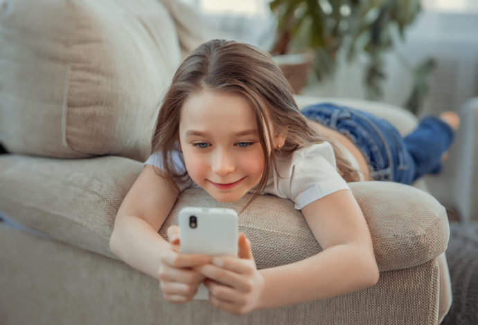 Beautiful little girl with smartphone. Leisure, children, technology and people concept
