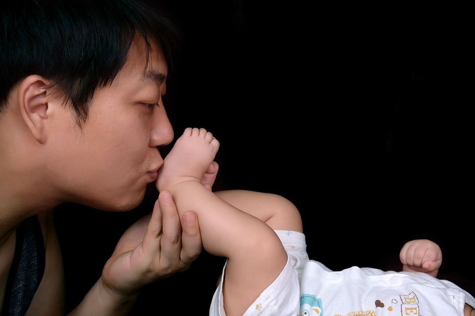 赤ちゃんの足にキスをするパパ