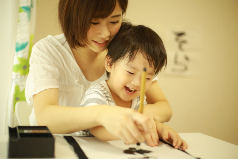 書き初めをする母親と子供