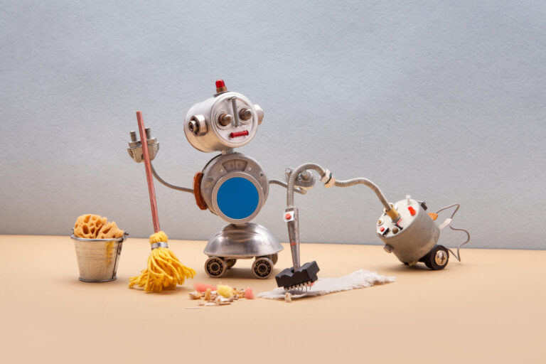Domestic robot janitor with vacuum cleaner machine disinfects sanitize room, vacuuming and sweeping floor and carpet. Autonomous disinfection service. Gray wall background. Copy space.