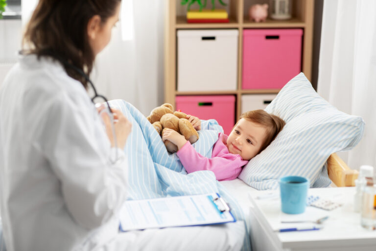 healthcare, medicine and people concept - doctor and sick little girl lying in bed at home