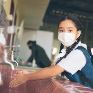 Asian student washing hands at the outdoor wash basin in the school. Preventing Contagious diseases, Plague. Kids health, protecting the virus Covid - 19 , Saving water, Cleaning, Running water.
