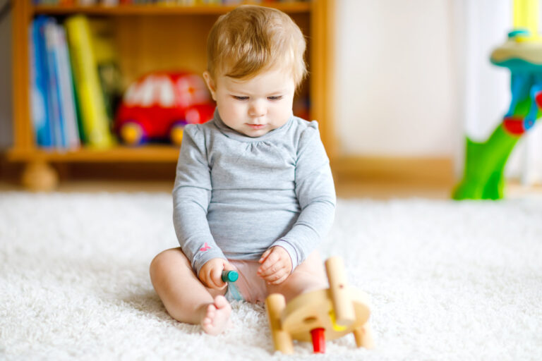 Adorable baby girl playing with educational toys . Happy healthy child having fun with colorful different wooden toy at home. 