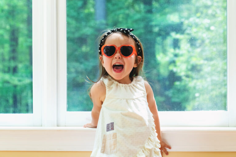 Happy toddler girl wearing sunglasses in her house