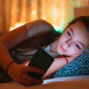 teen girls lying in bed at night and using smartphone. Insomnia and the harm of the smartphone before going to bed. Not healthy sleep. Dependence on social networks in adolescents.