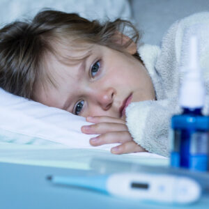 Sick and tired child wrapped with blanket lying in bad. Close up. Illness treatment at home concept.