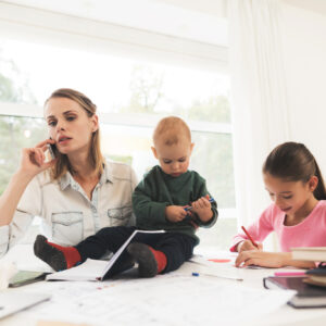 A woman works during maternity leave at home. A woman works and cares for a children at the same time. Mother of two children finds time for work at home.